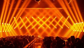 オレンジのビームが客席の上で交差しているライブ会場